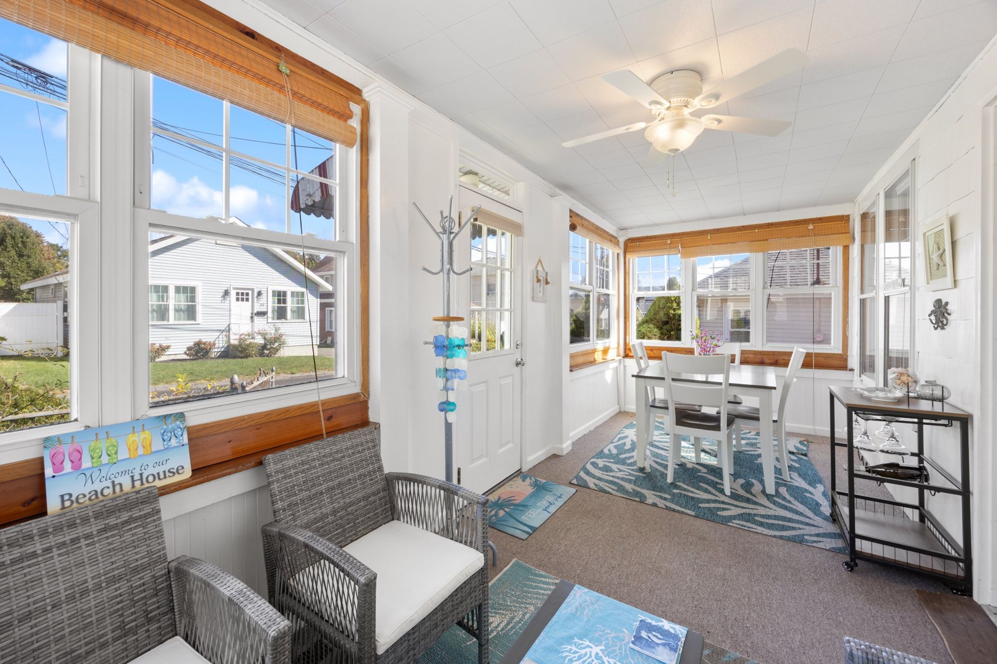 Enclosed sunporch with wicker chairs, dining table, and windows on three sides